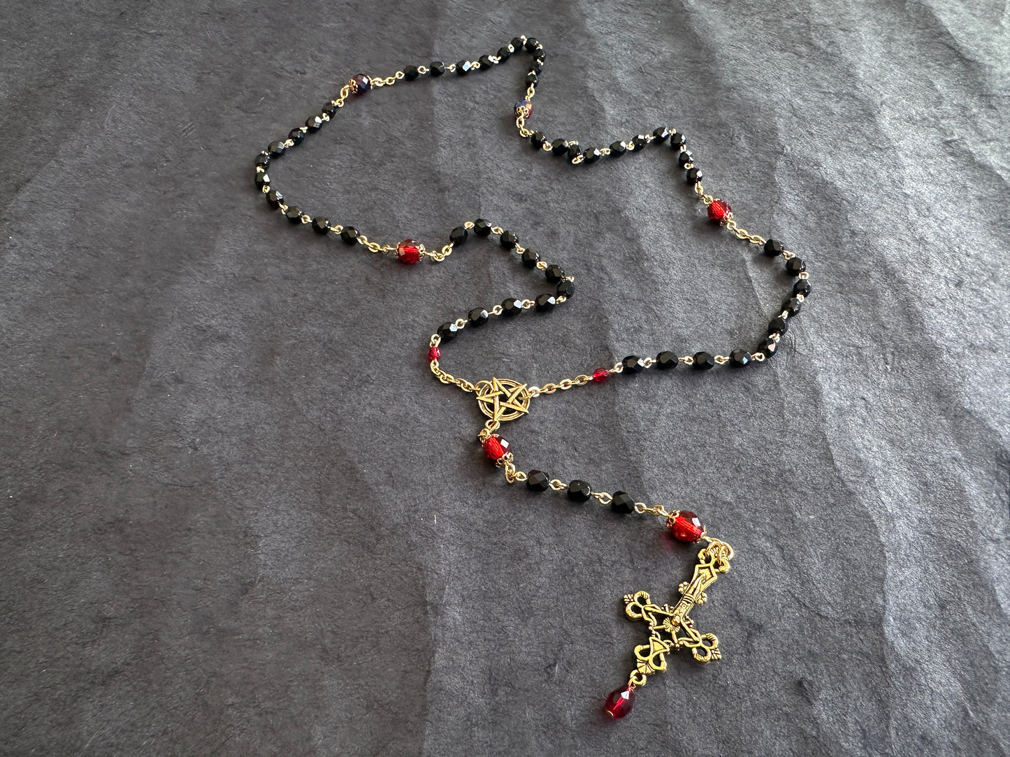 Black bead and gold rosary with red drop