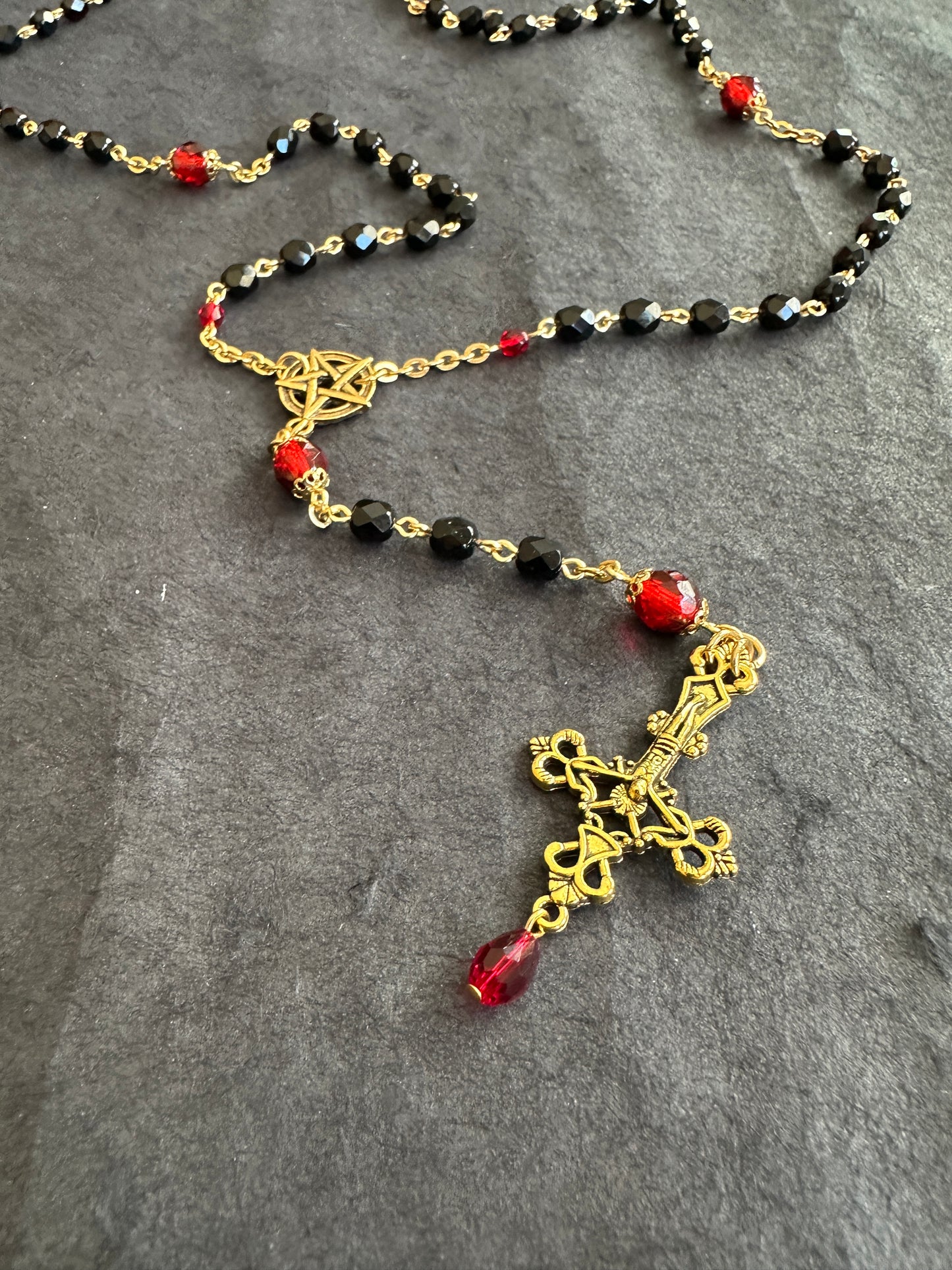 Black bead and gold rosary with red drop