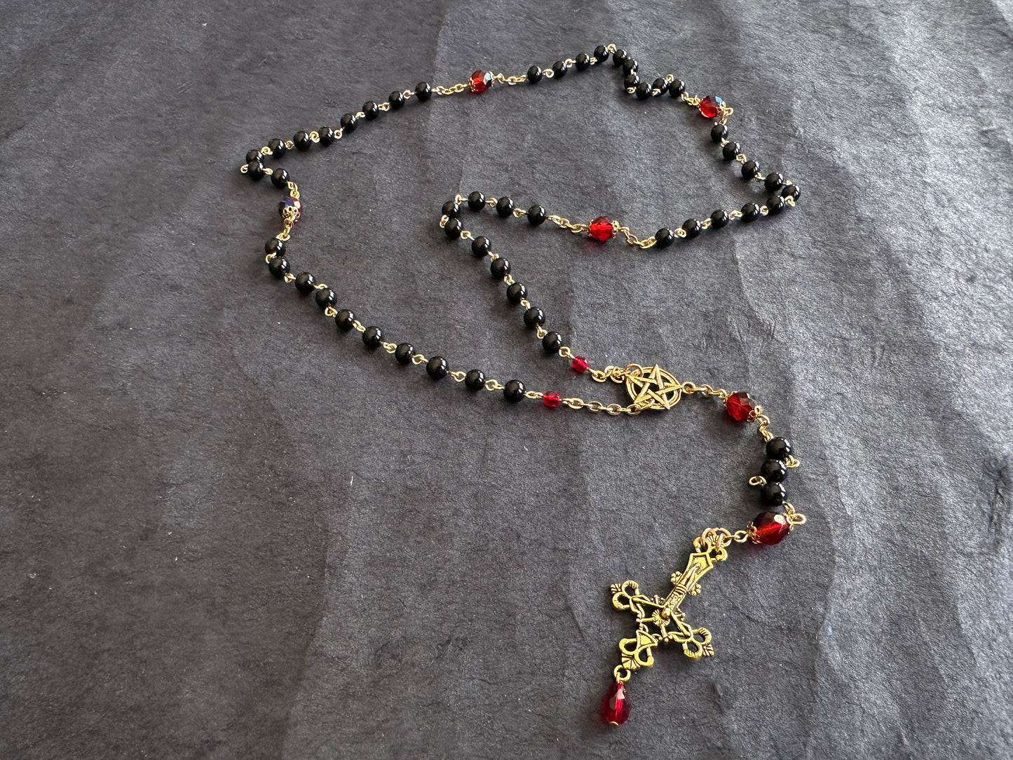 Black bead and gold rosary with red drop