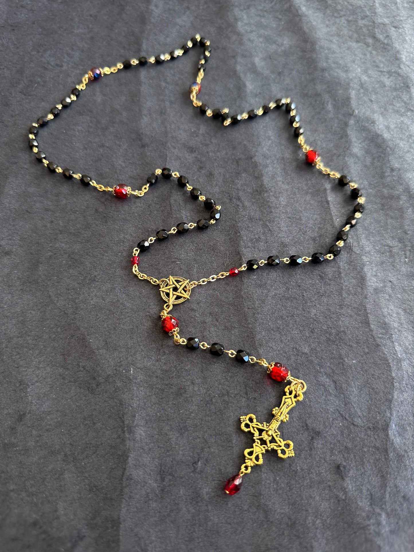 Black bead and gold rosary with red drop