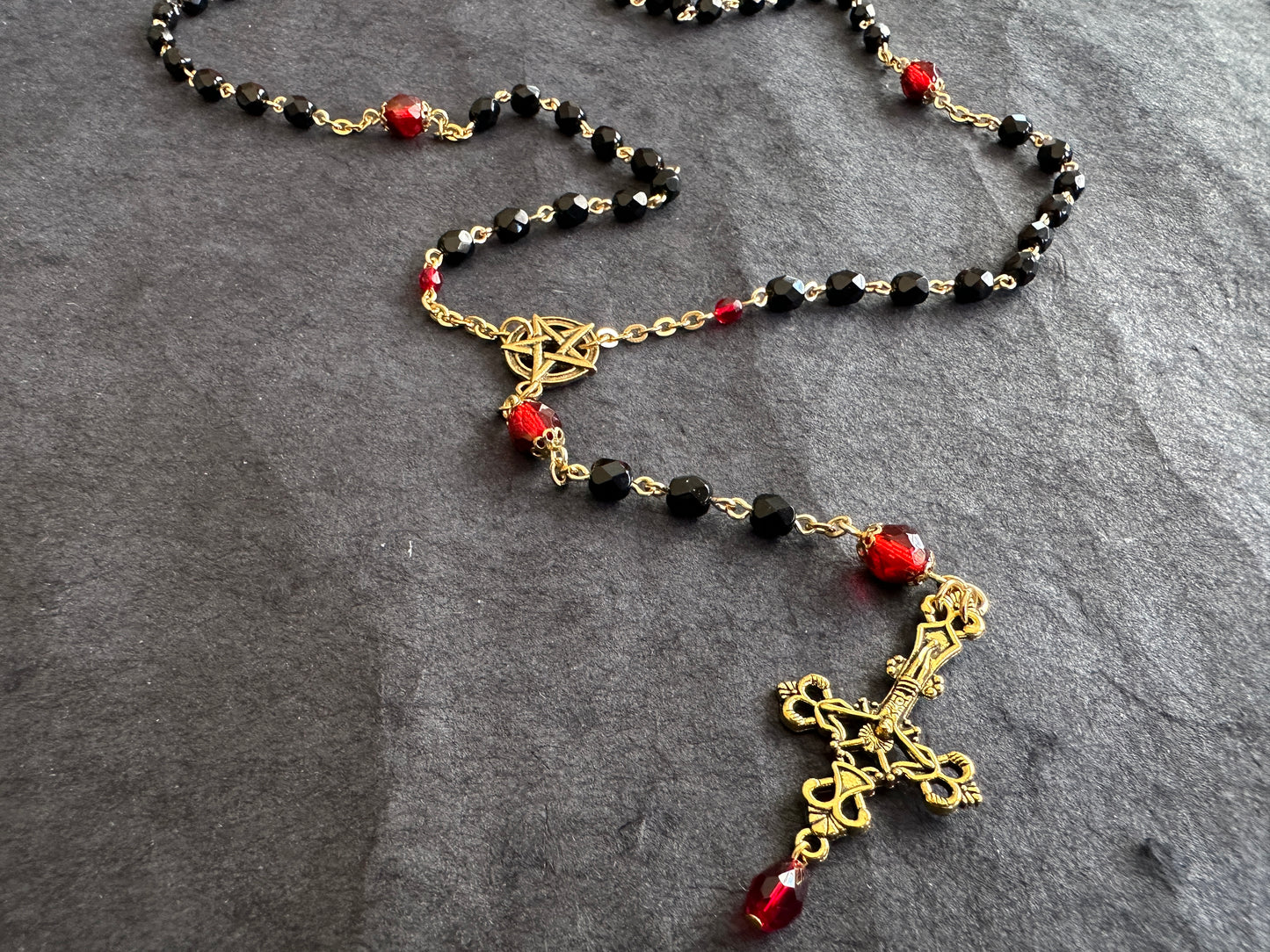 Black bead and gold rosary with red drop